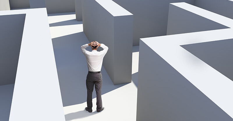 Rear View Of Businessman Standing In Maze Being Captured